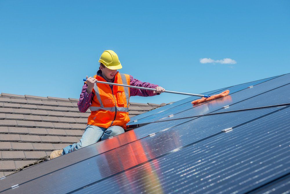 Young Worker Cleaning Solar Panels On House Roof — Solar Panel Cleaning in Hervey Bay, QLD