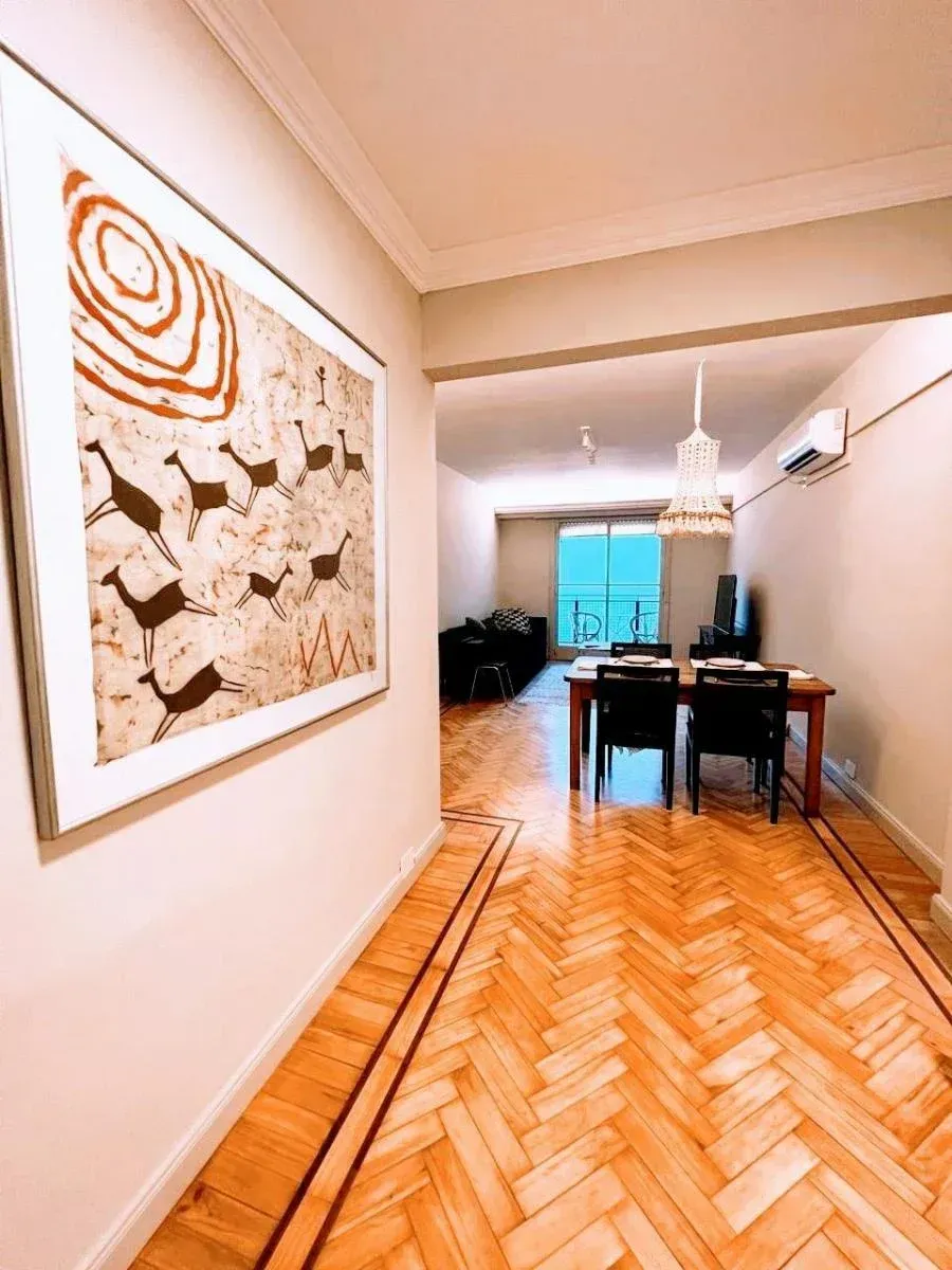 Edificio alto con vegetación que desciende por la fachada. Base de piedra gris, hileras de ventanas y un cielo despejado.