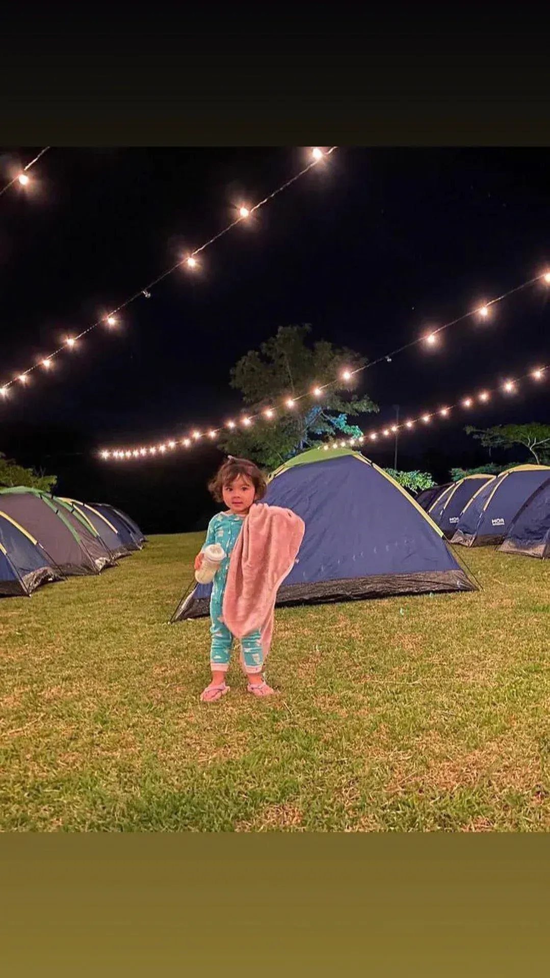 uma menina está parada na frente de uma barraca segurando uma toalha.