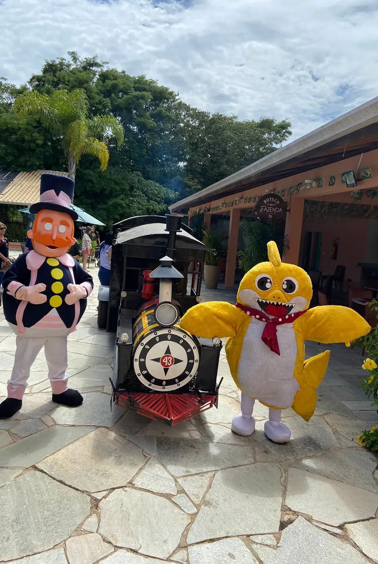 um casal de mascotes parados ao lado de um trem.