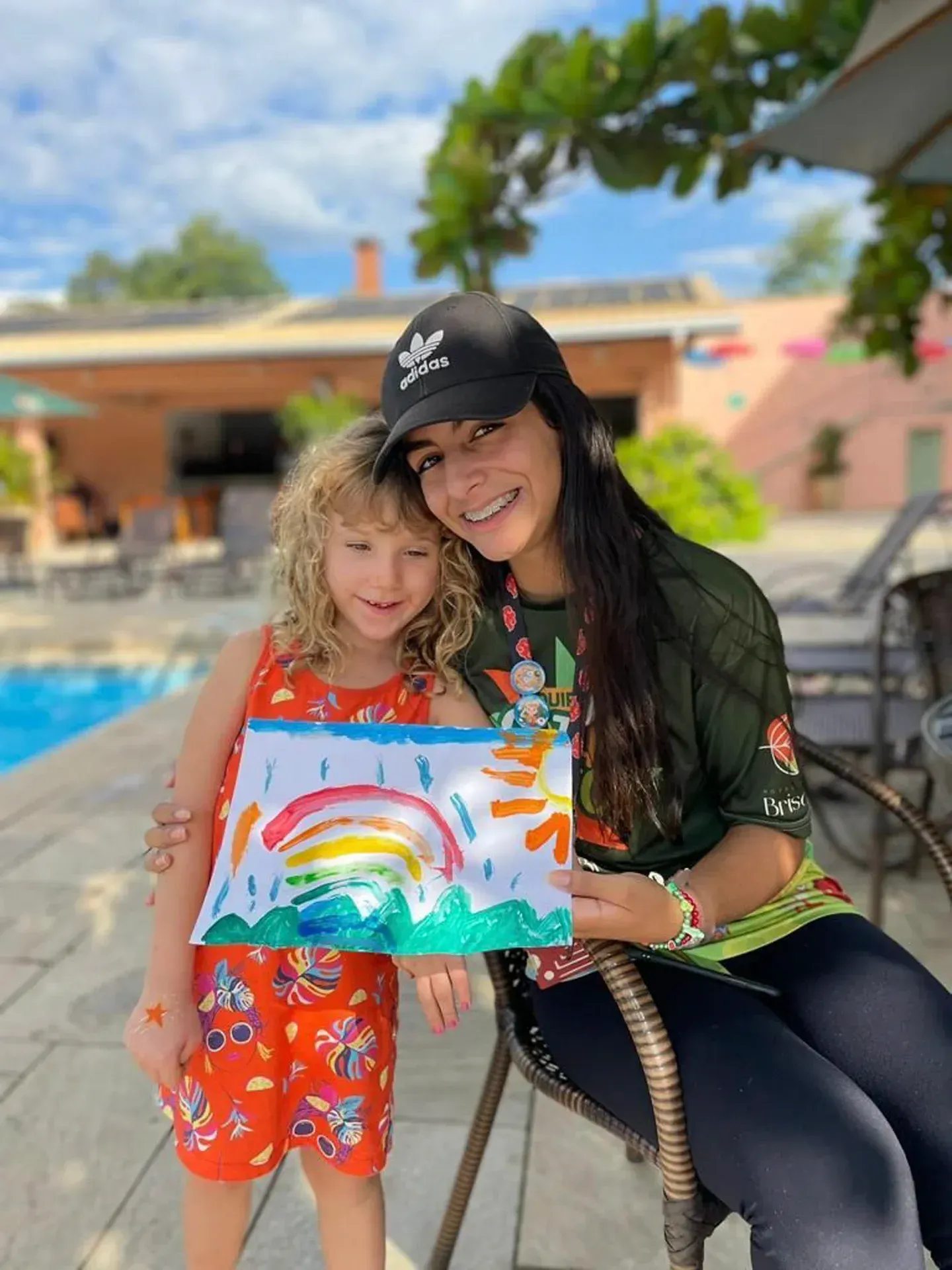 uma mulher e uma menina estão segurando o desenho de um arco-íris.