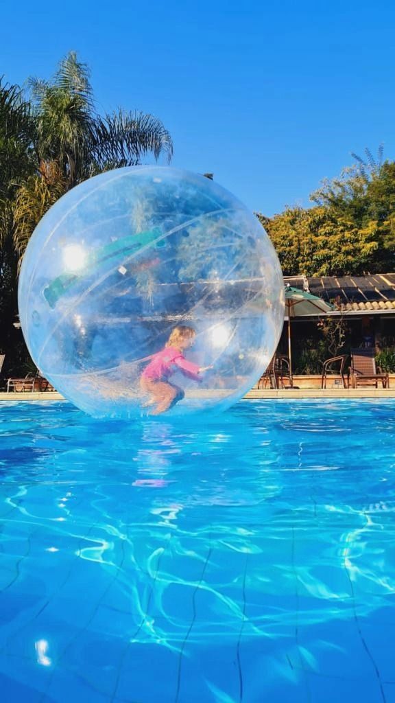 uma criança está brincando dentro de uma bola inflável em uma piscina.
