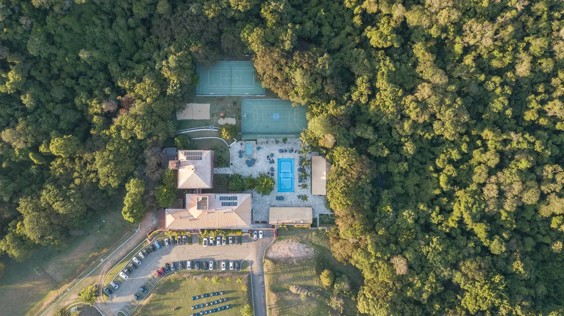 uma vista aérea de uma casa cercada por árvores e uma piscina.