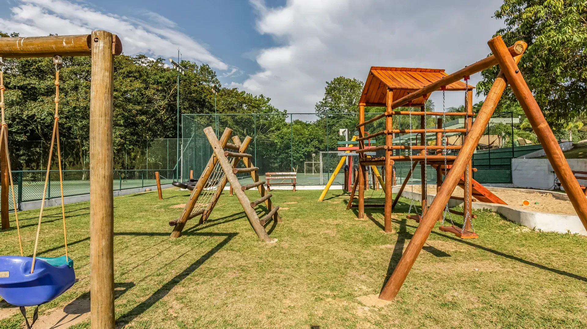 um playground de madeira com balanços e escorregador em um parque.