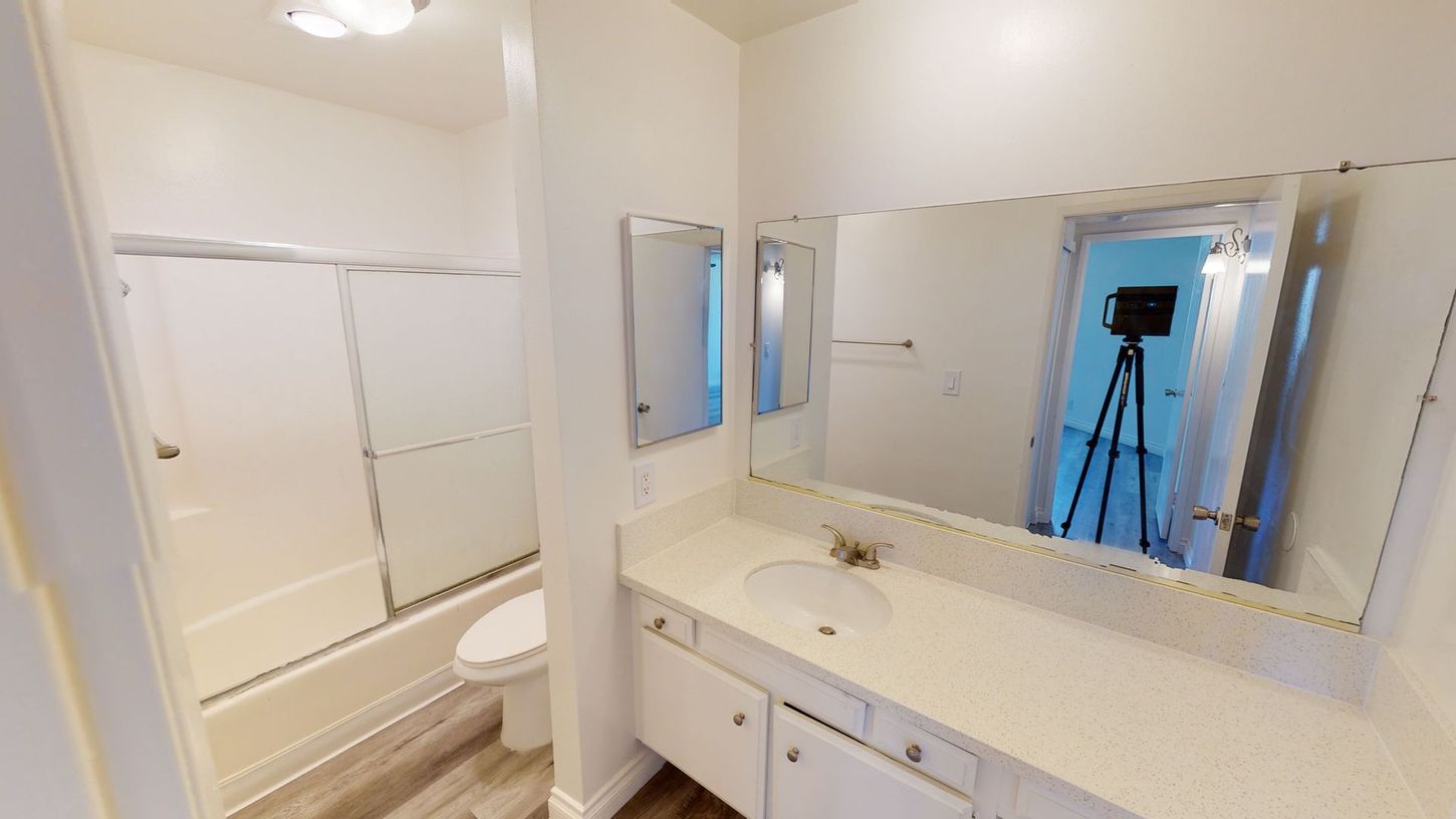 Bathroom interior with white walls, vanity, mirror, and shower.