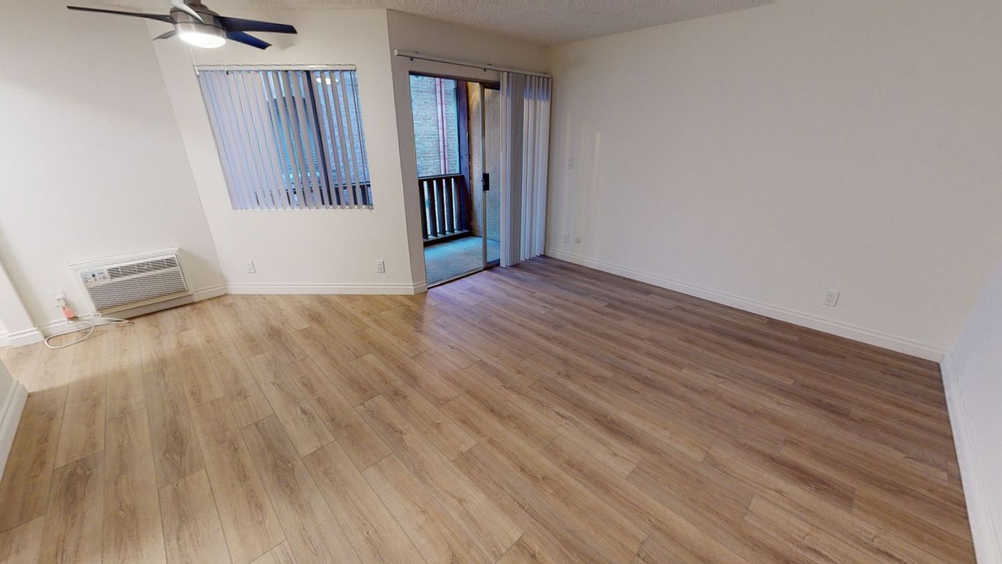 Empty room with wood floors, blinds, and a door to a balcony.
