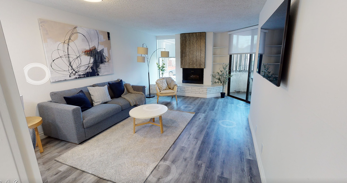 Living room with gray sofa, rug, coffee table, fireplace, and large abstract art.