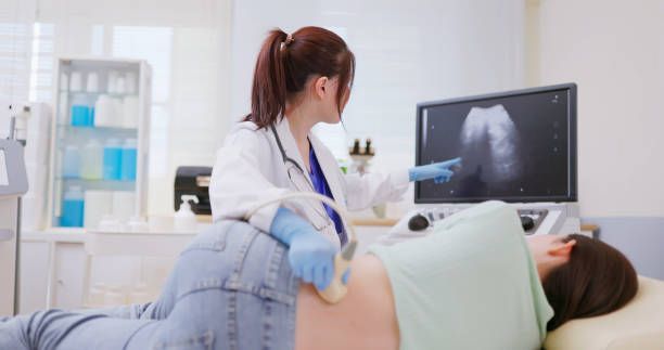 A pregnant woman is getting an ultrasound from a doctor.