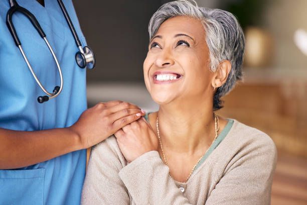 A nurse is holding the shoulder of an elderly woman.