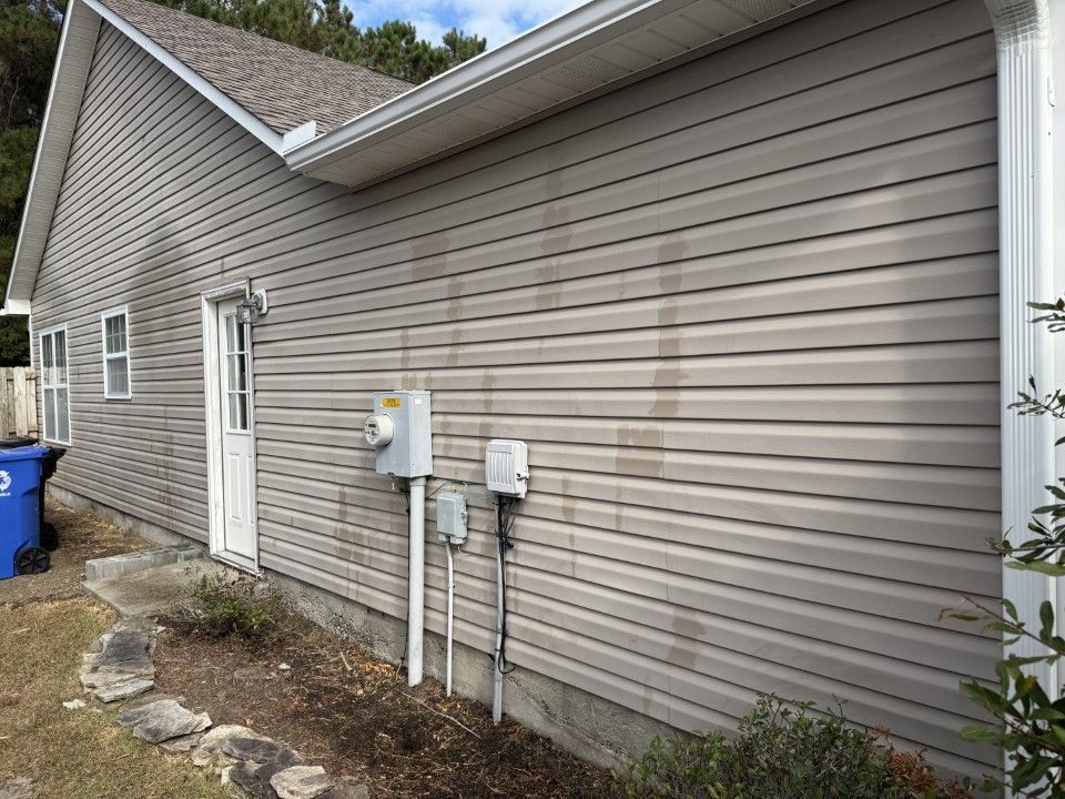 Tan vinyl siding on a house with dark streaks from water runoff; exterior view.