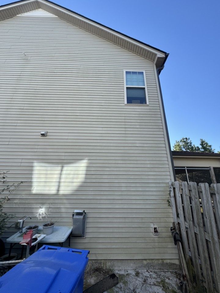 Tan house exterior with siding, a window, and a wooden fence.