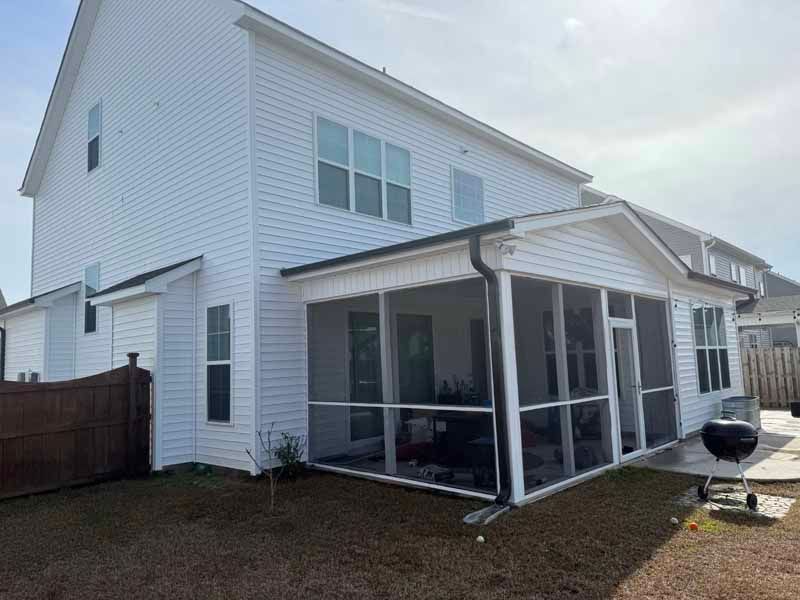 White house with a screened porch and grilling area.