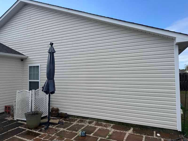 Beige vinyl siding on a house exterior, with a closed umbrella and patio.