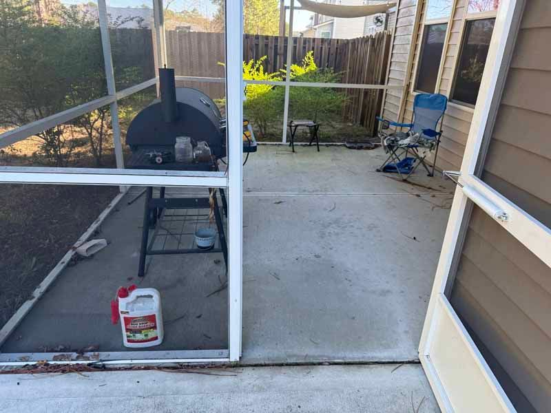 Patio with a grill and outdoor furniture inside a screened enclosure.
