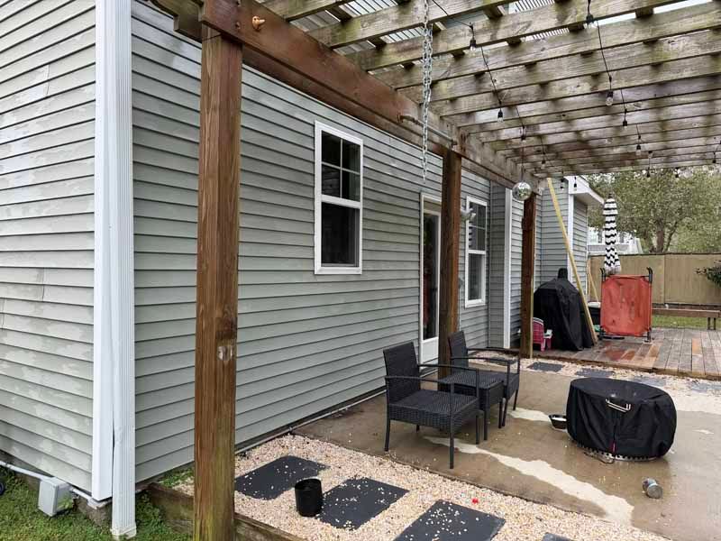 Patio with a pergola, gray siding, seating area, and outdoor grill.