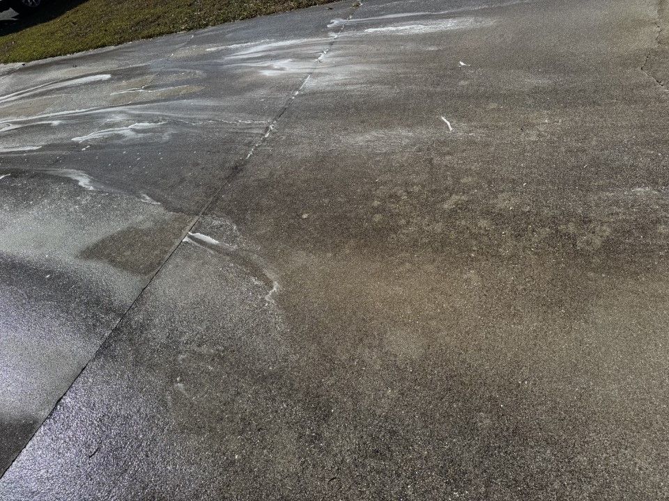 Concrete driveway stained with white residue and dark patches.
