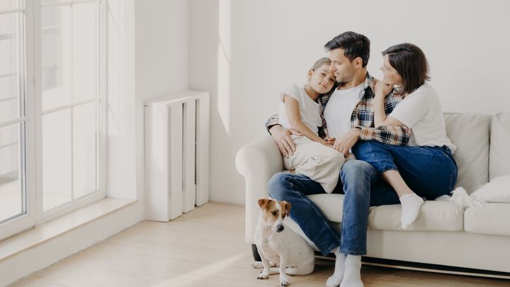A family is sitting on a couch with a dog.