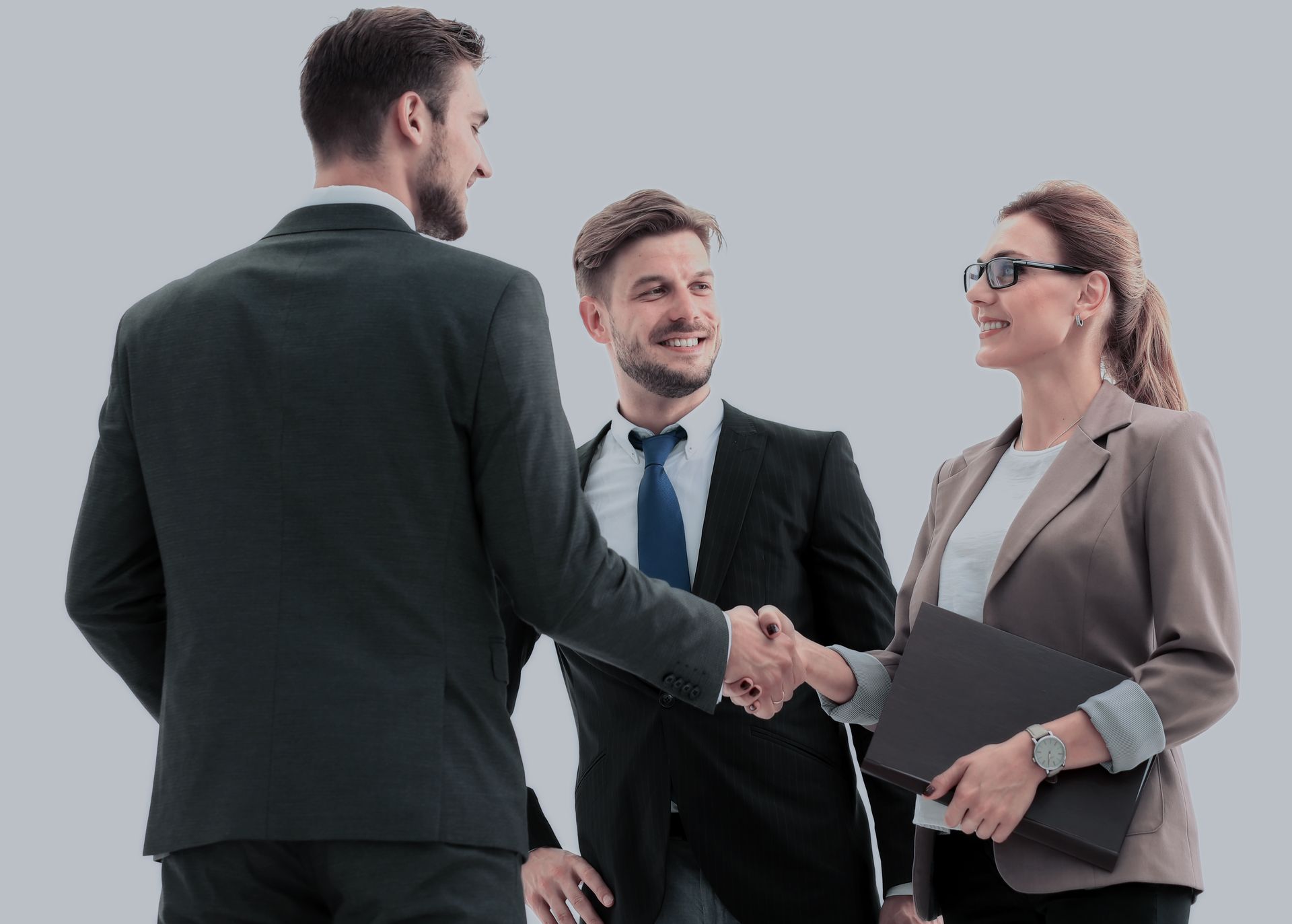 Three professionals in business attire shaking hands in a studio setting