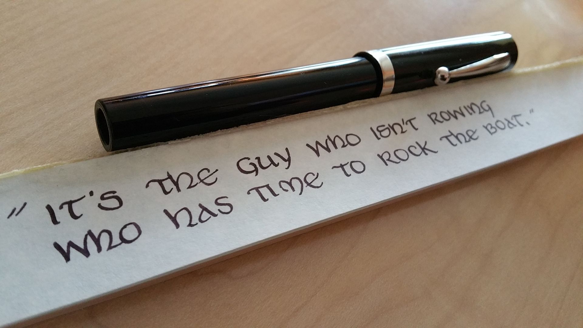 A pen is sitting on a piece of paper that says it 's the guy who isn 't rowing