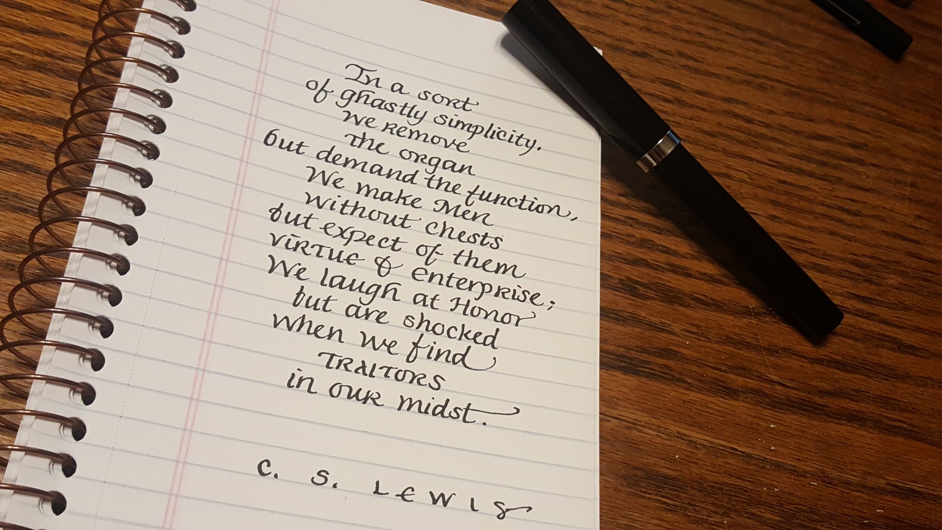 A spiral notebook has a quote from c.s. lewis written on it