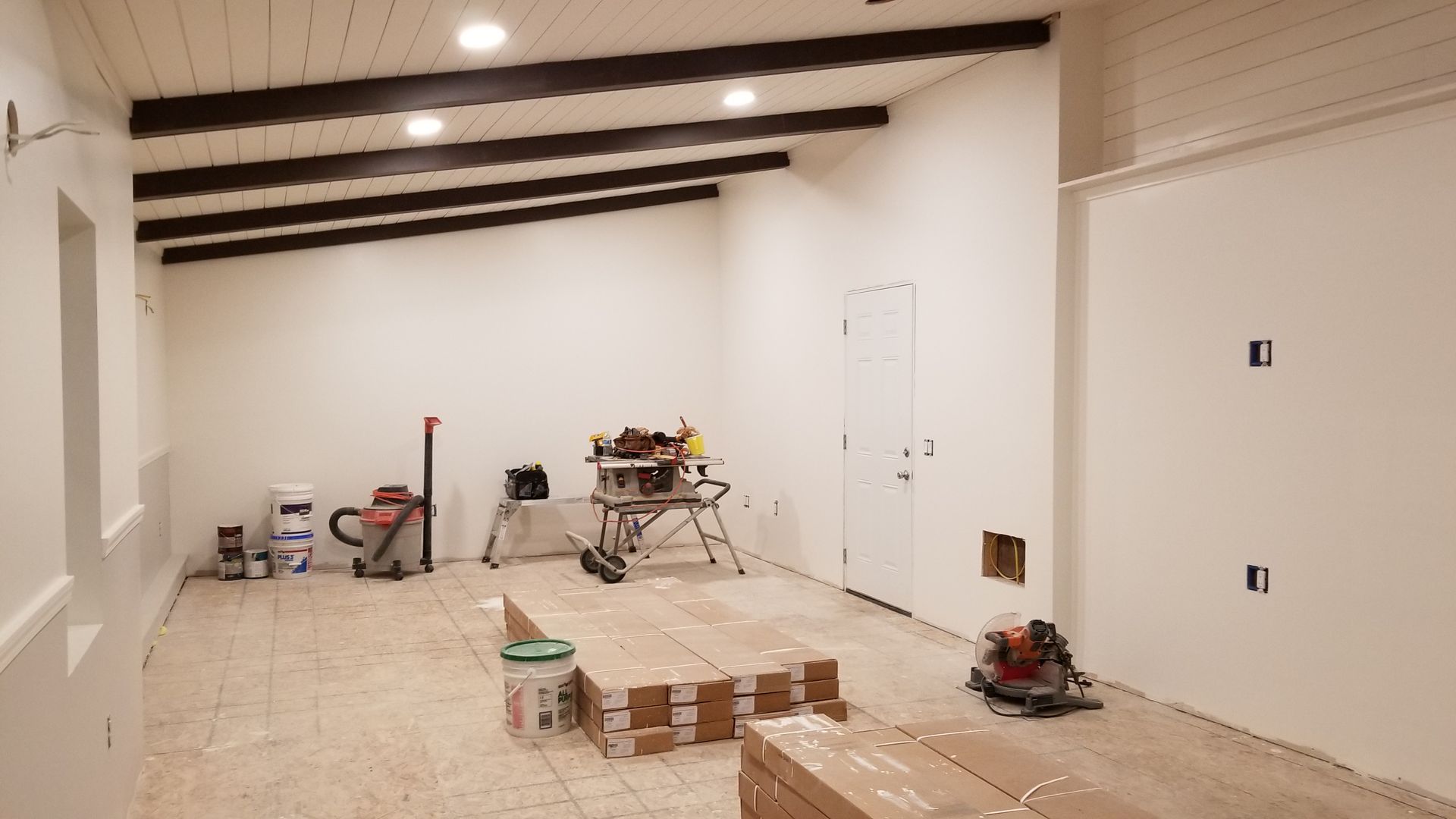 A room with white walls and wooden floors is being remodeled.