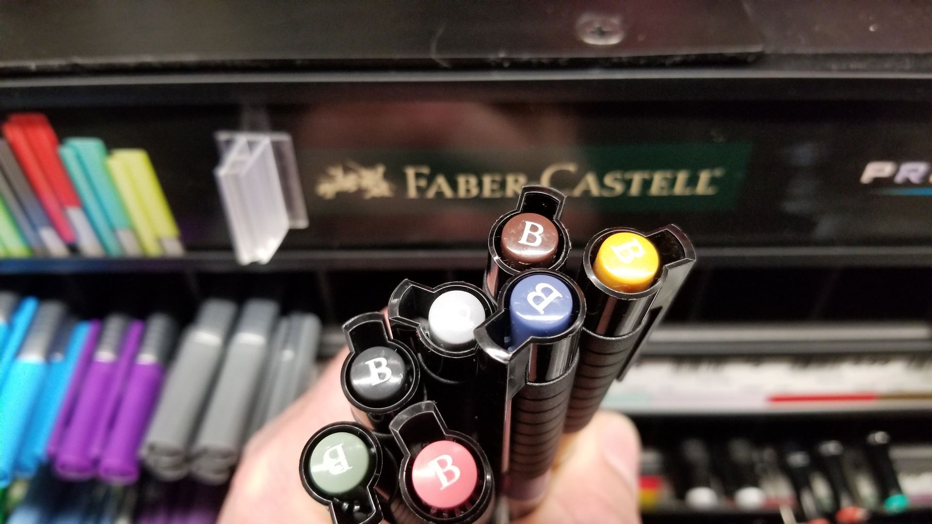 A person is holding a bunch of faber castell pens
