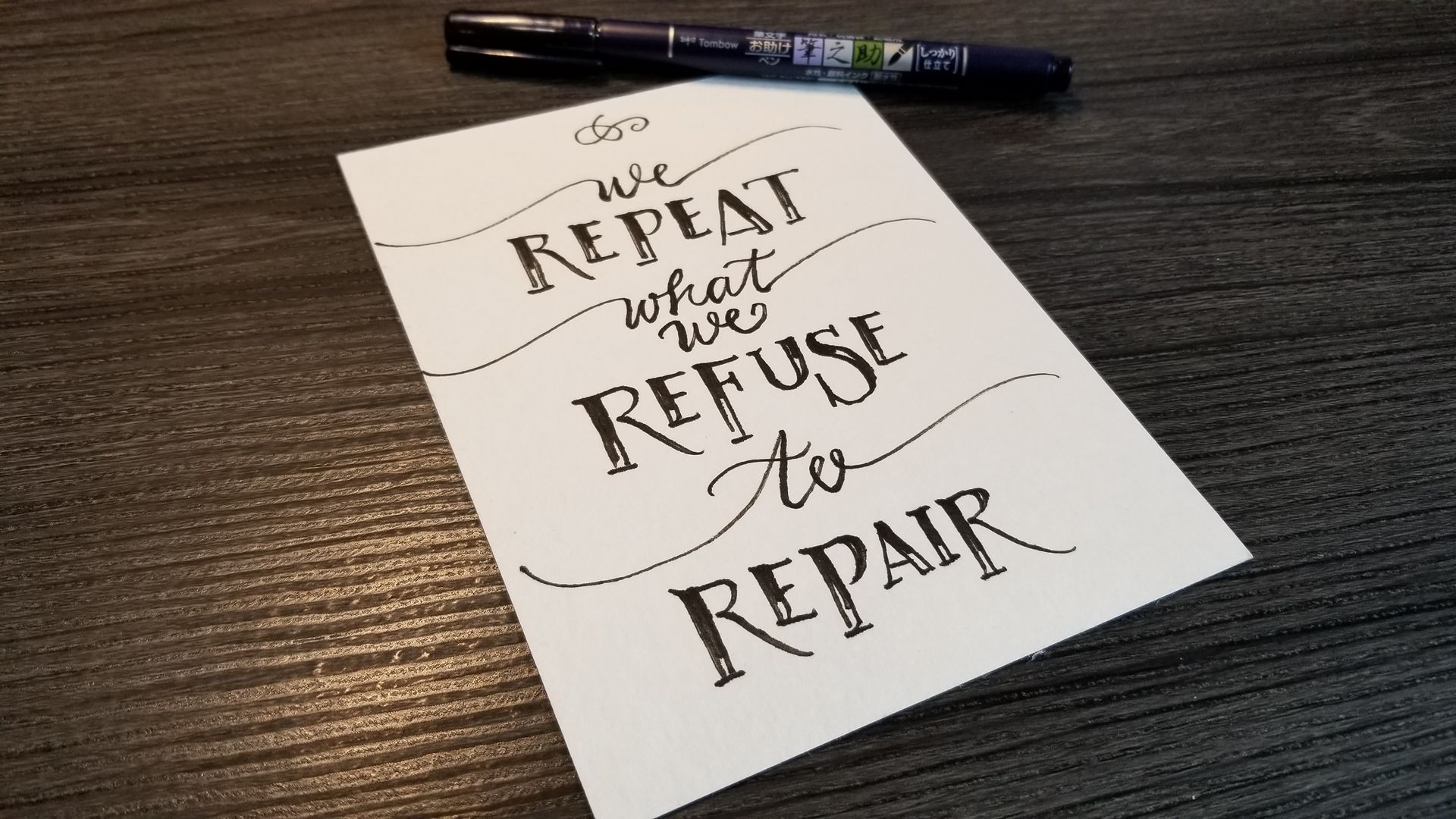 A piece of paper with the words `` we repeat what we refuse to repair '' written on it