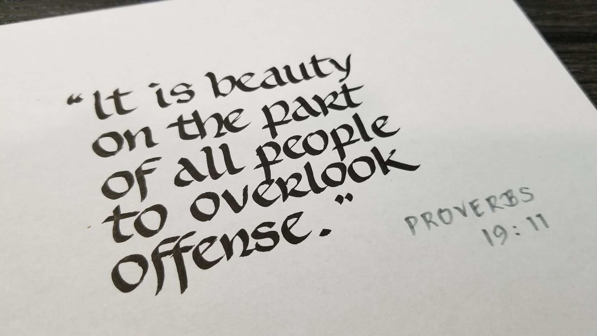 Proverbs 19:11 is written on a piece of paper