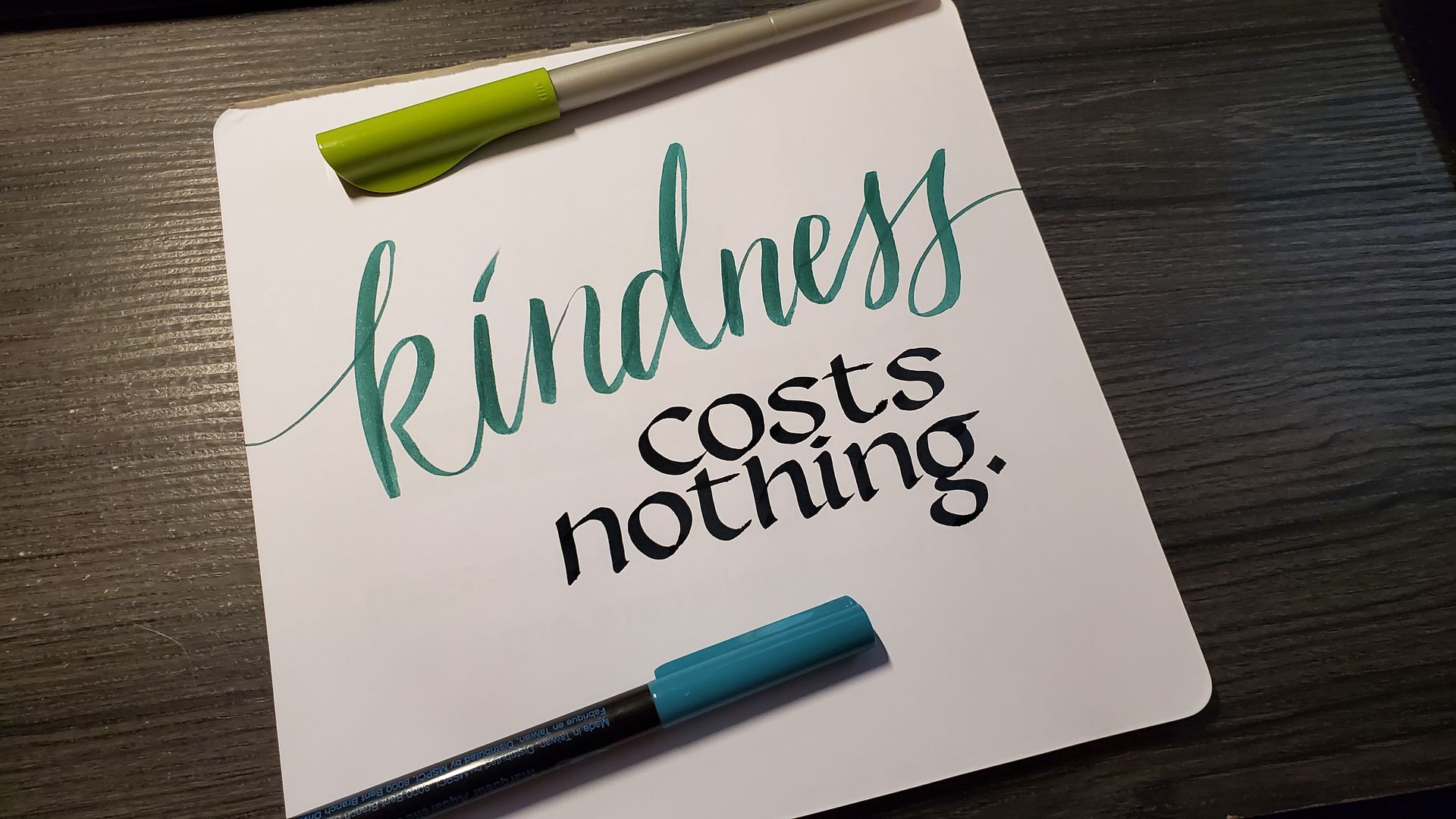 A piece of paper with the words `` kindness costs nothing '' written on it.