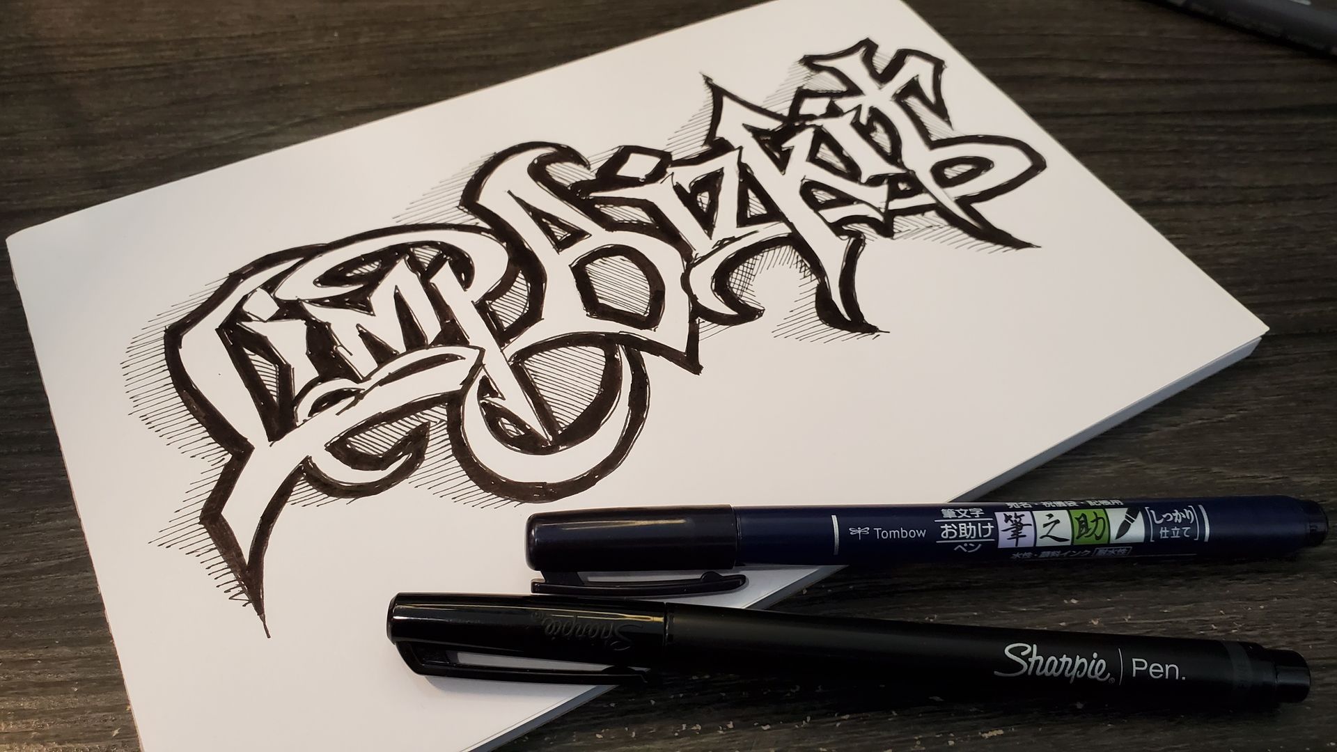 A piece of paper with graffiti on it and two pens on it