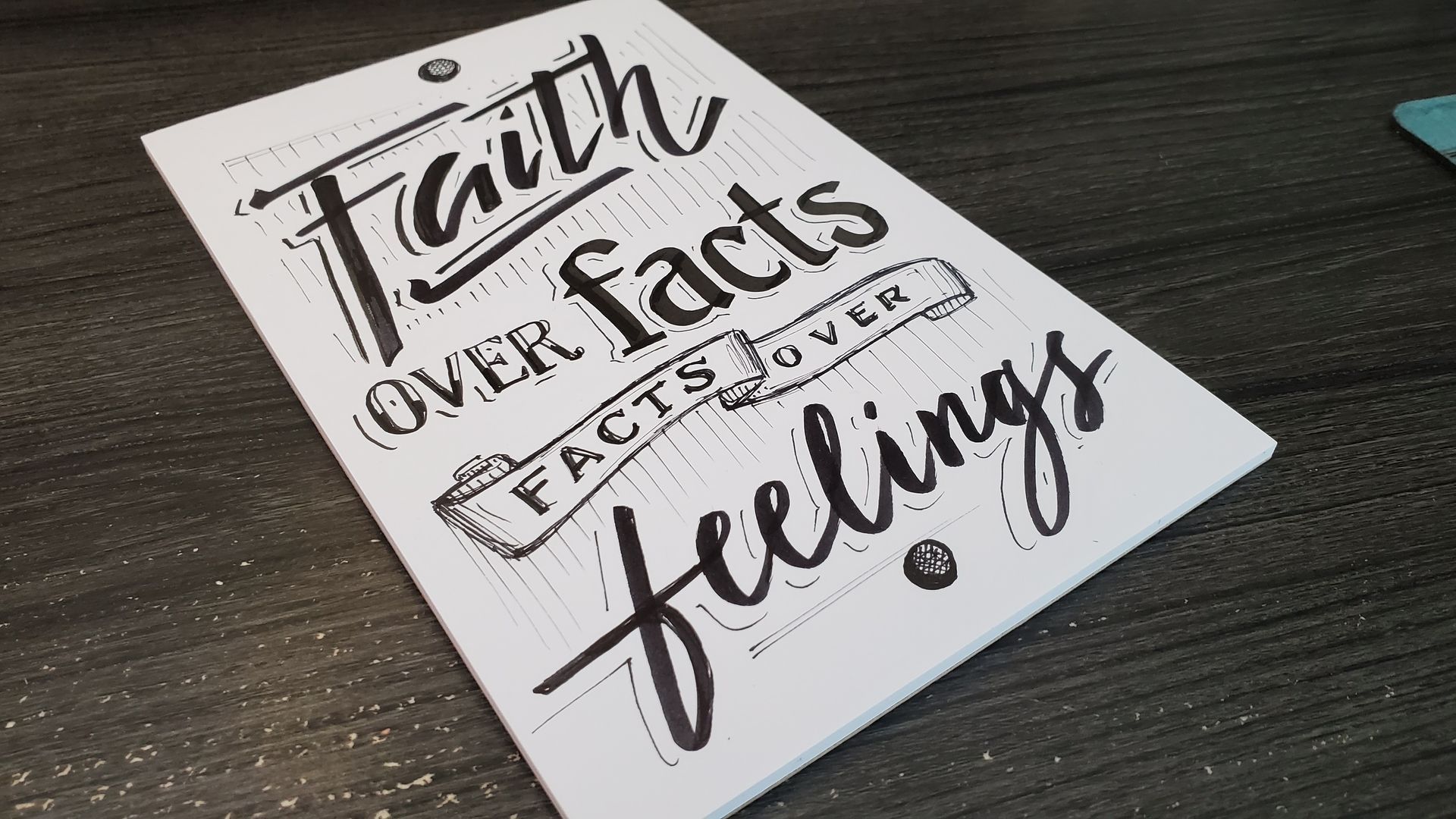 A piece of paper that says faith over facts facts over feelings