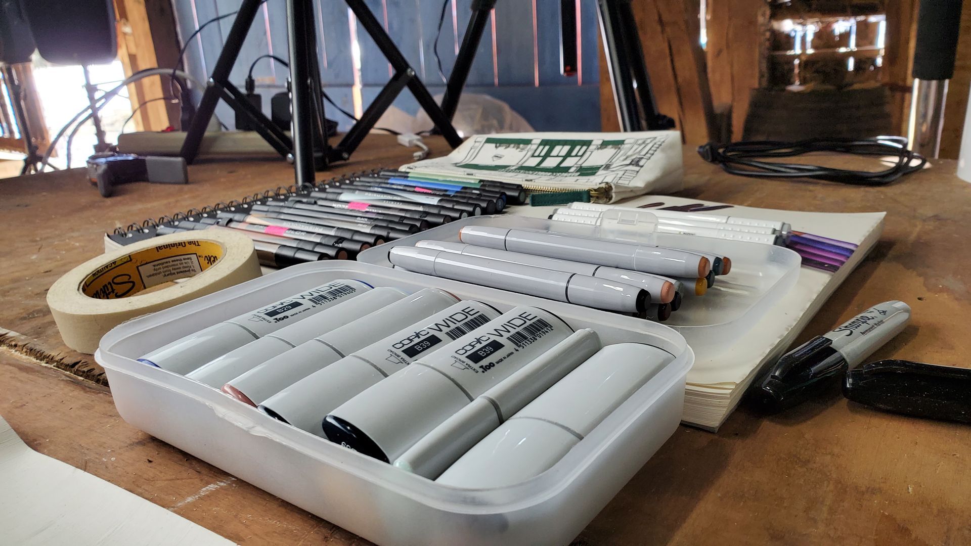 A tray of markers is sitting on a wooden table.