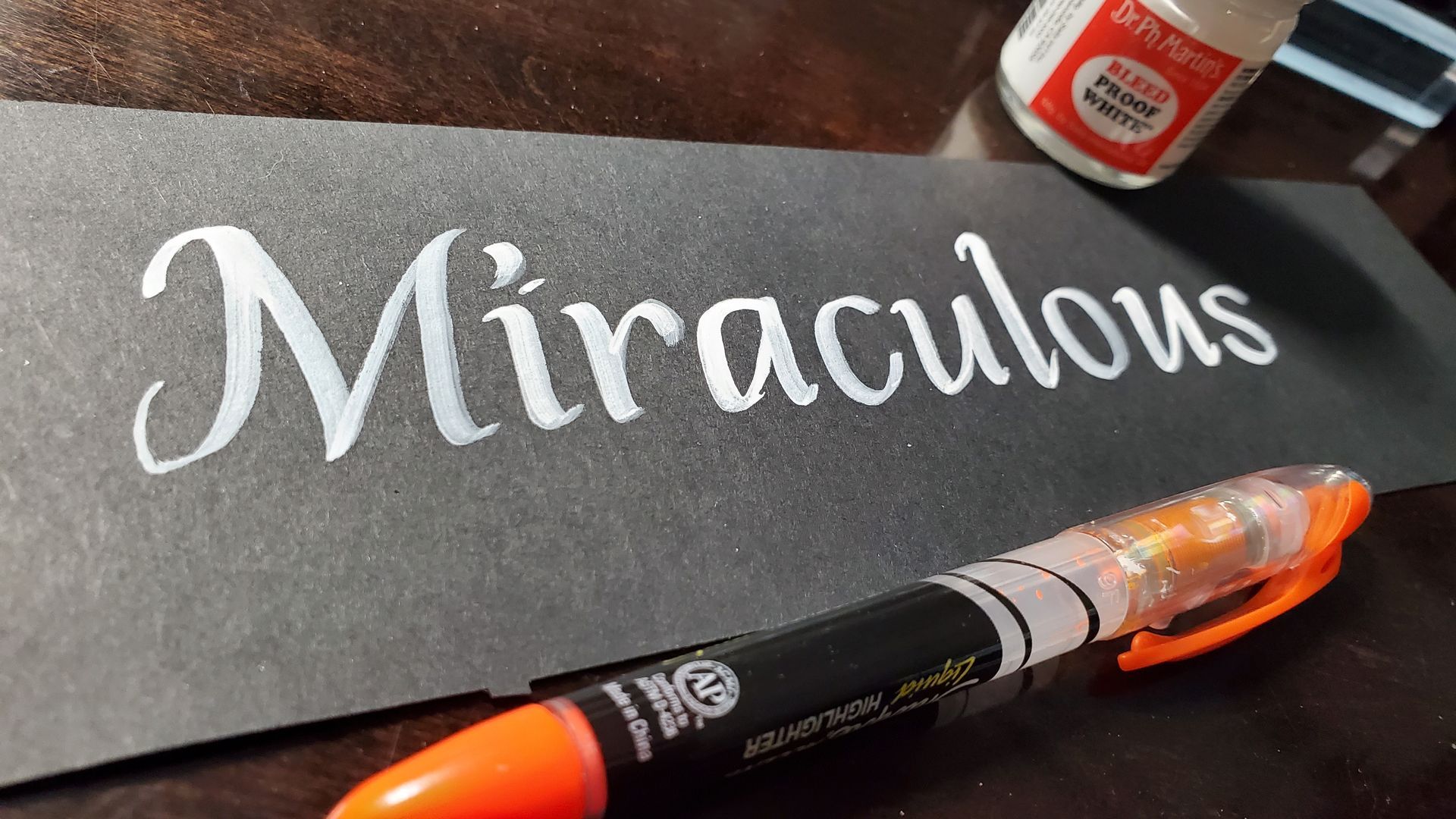 A black piece of paper with the word miraculous written on it