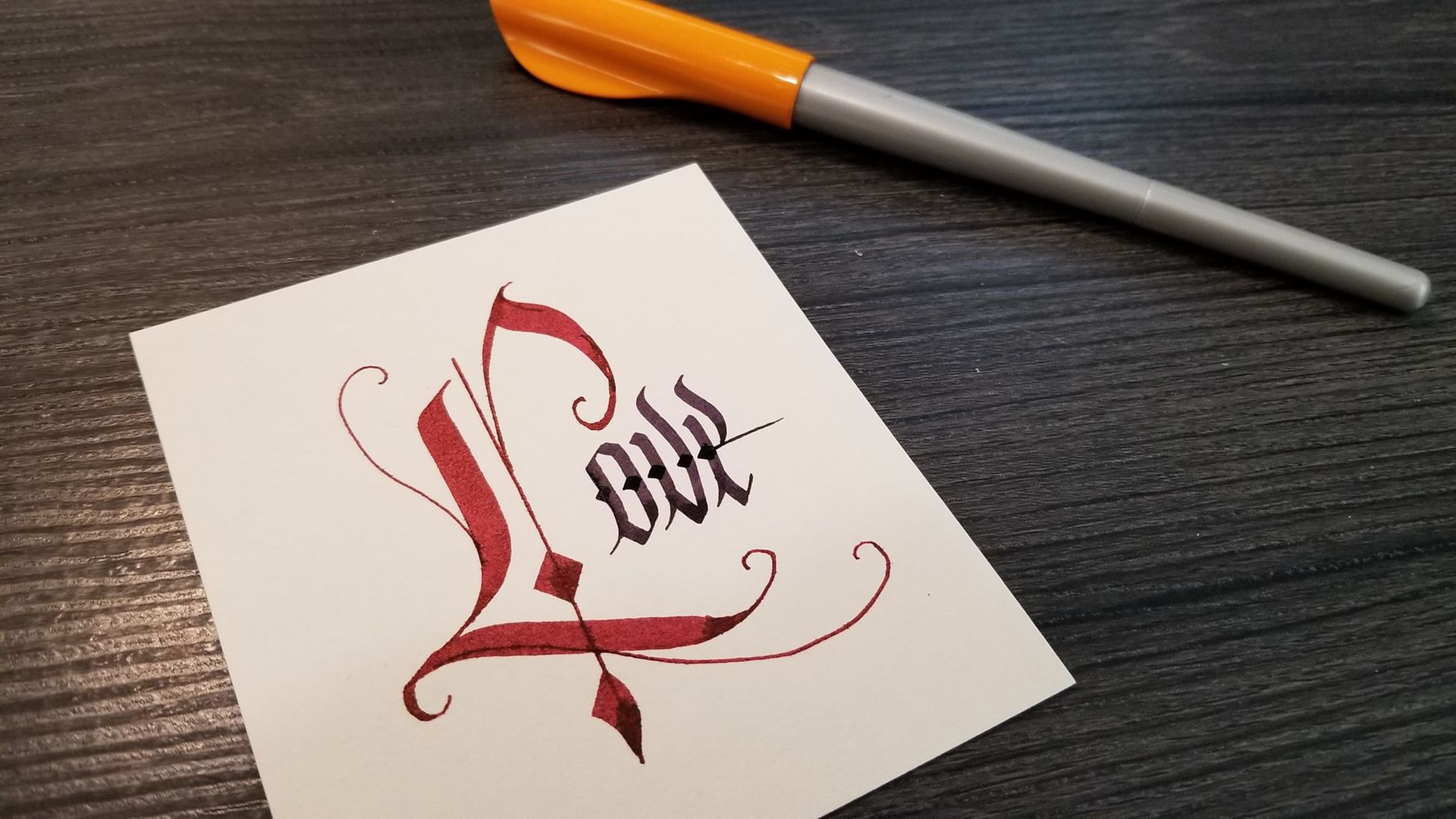 A pen is sitting next to a piece of paper with the word love written on it.