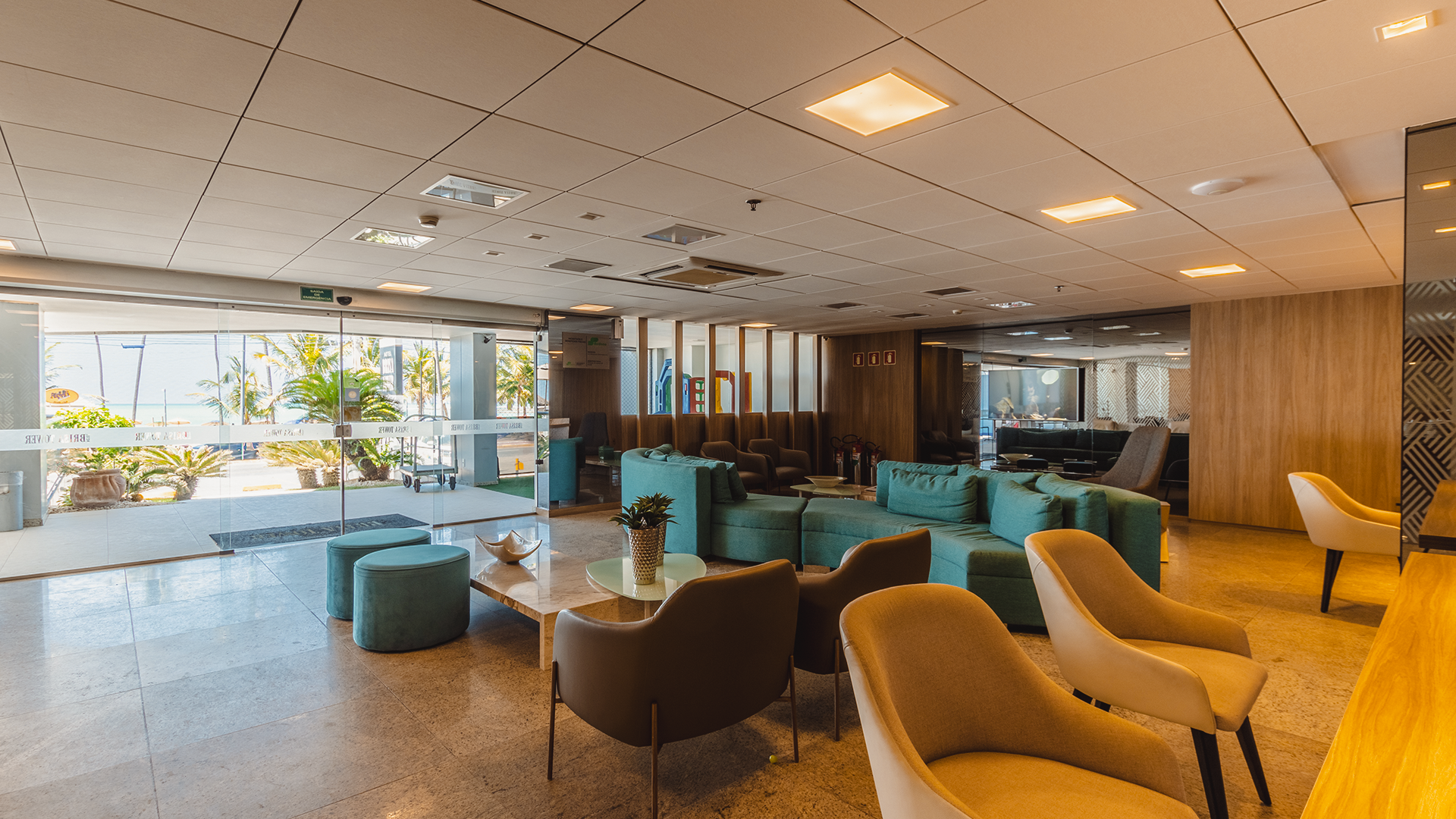 Piscina com espreguiçadeiras, mesas e guarda-sóis perto da praia em um ambiente ensolarado.