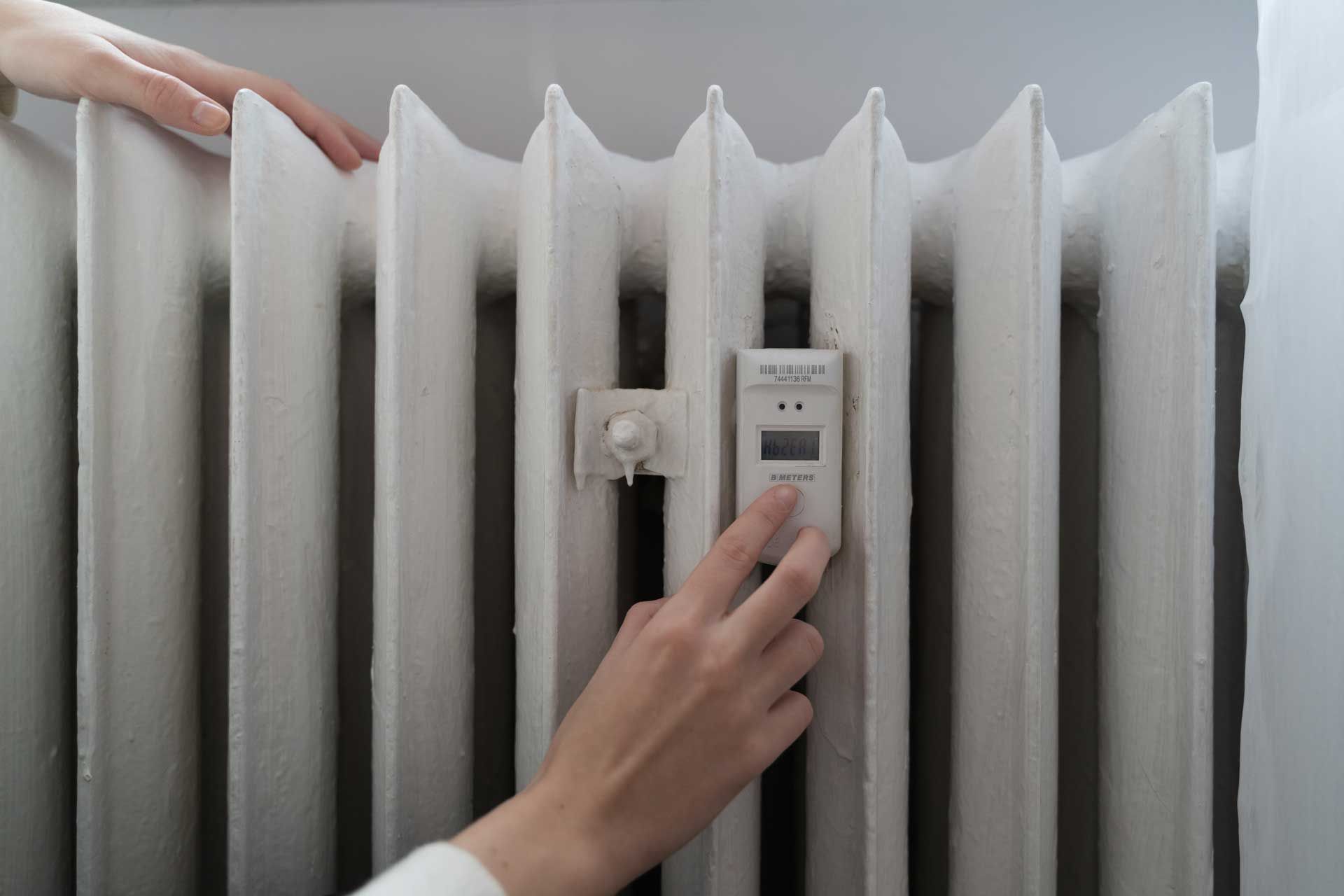 Woman near the home radiator with temperature sensor Woman near the home radiator with temperature sensor