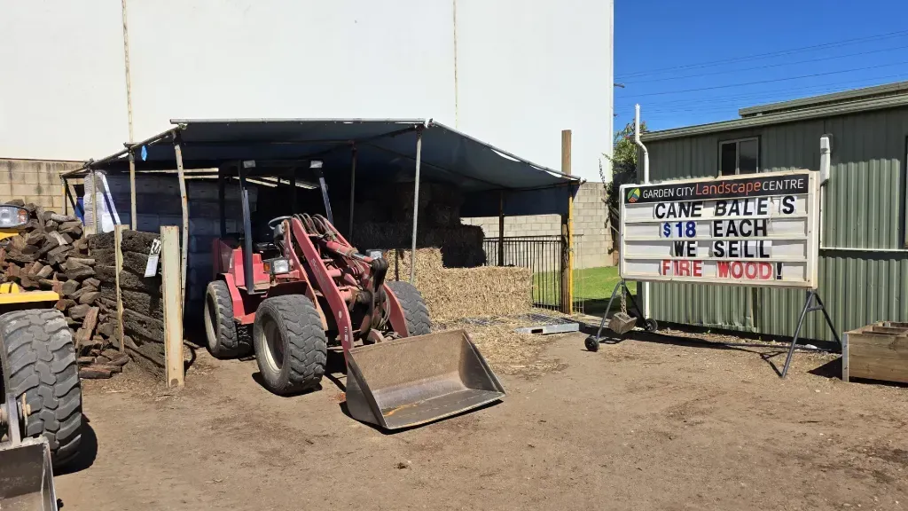 A mini digger is parked in front of a building next to a sign that says free wood.