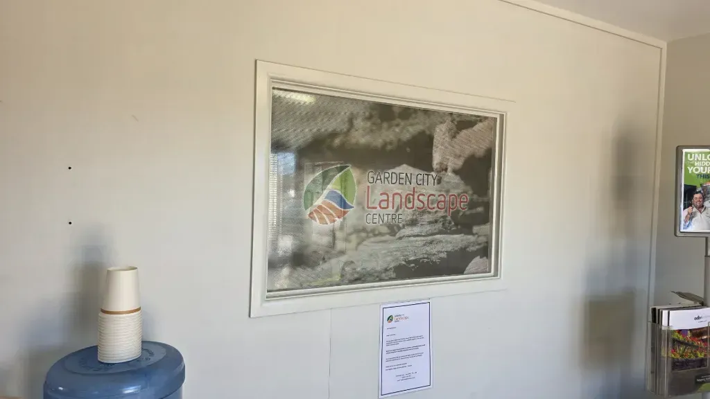 A picture with the garden city landscape centre logo is hanging on a wall next to a water cooler.