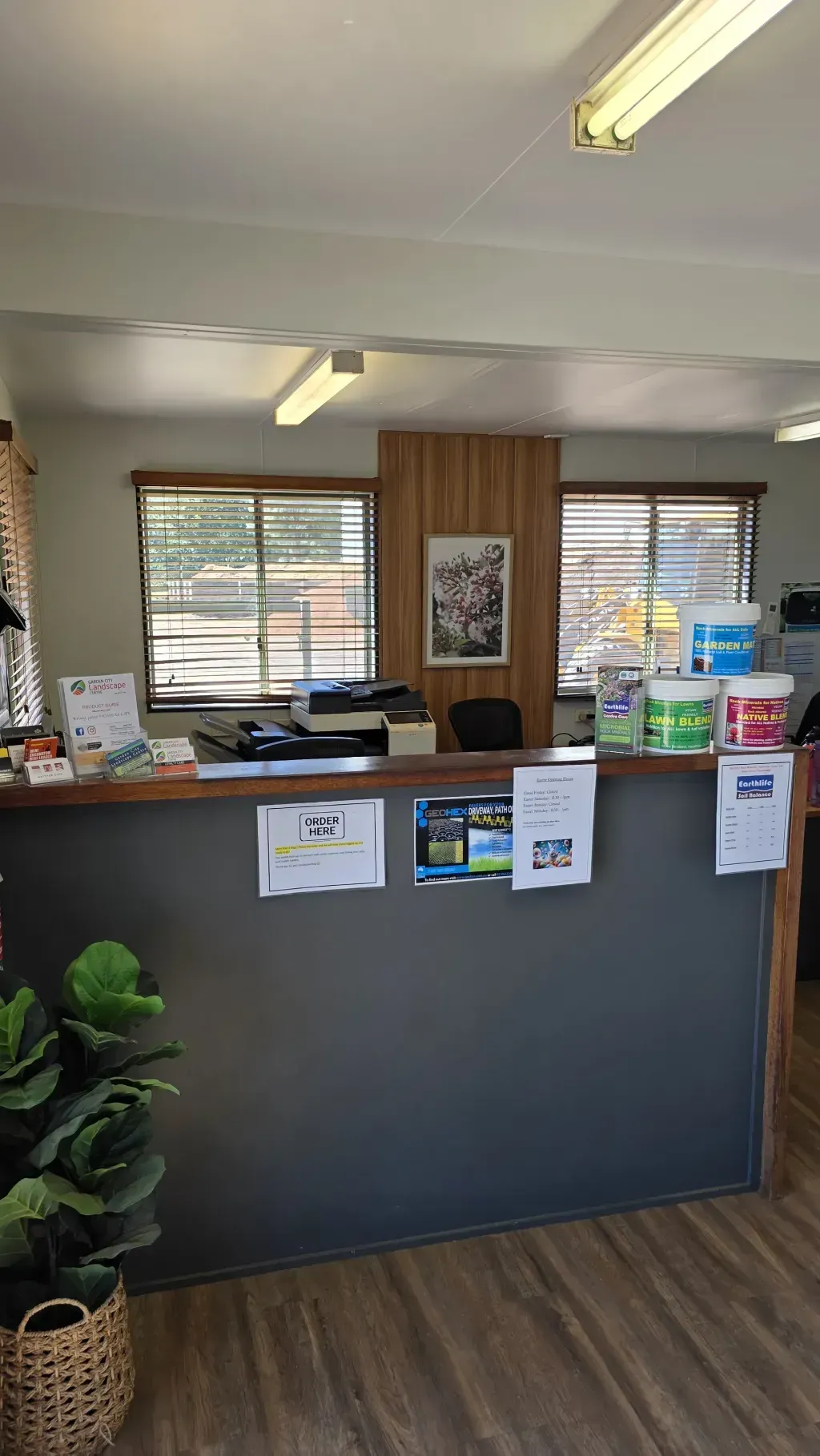 A reception desk in a garden city landscape centre with a lot of lawn and garden care supplies on it.