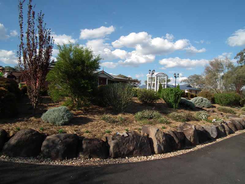 A landscape with rocks and trees and a house in the background