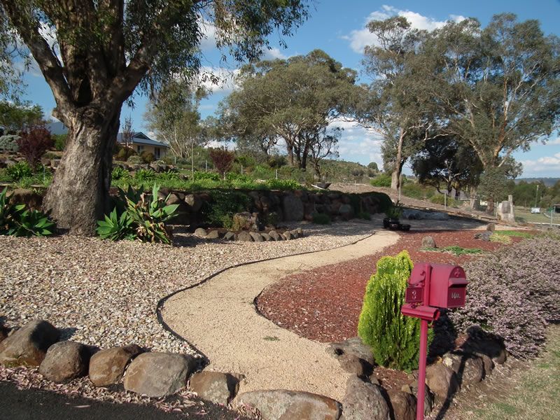A red mailbox is in the middle of a gravel path