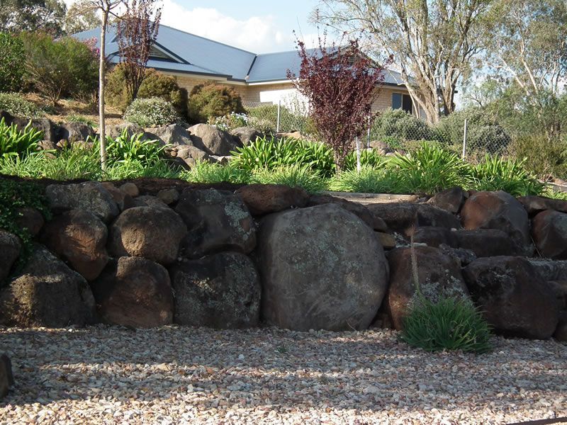 A large rock wall with a house in the background
