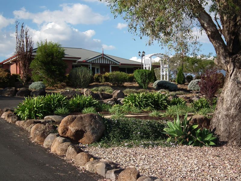 A large house is surrounded by rocks and plants