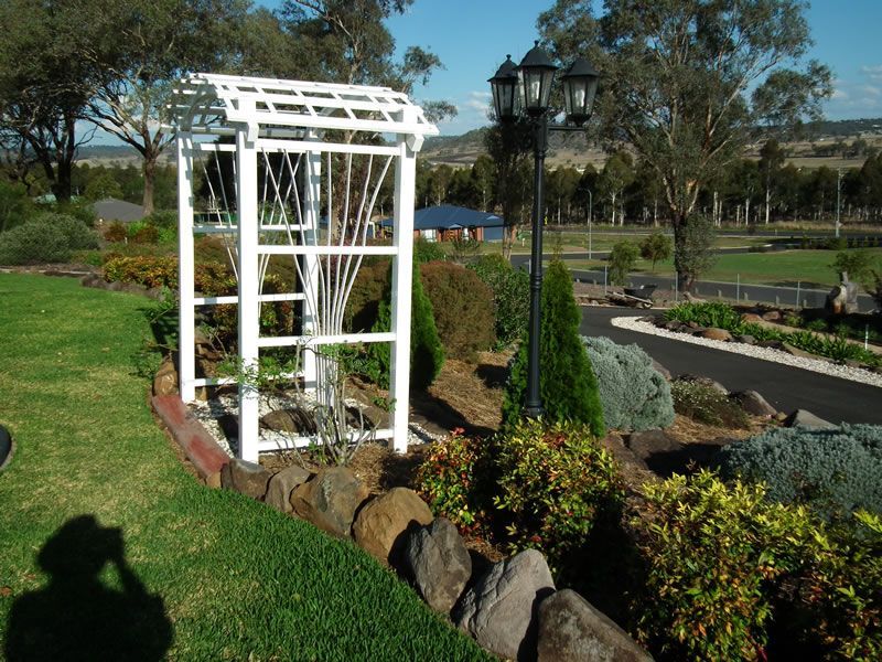 A white gazebo sits in the middle of a lush green garden