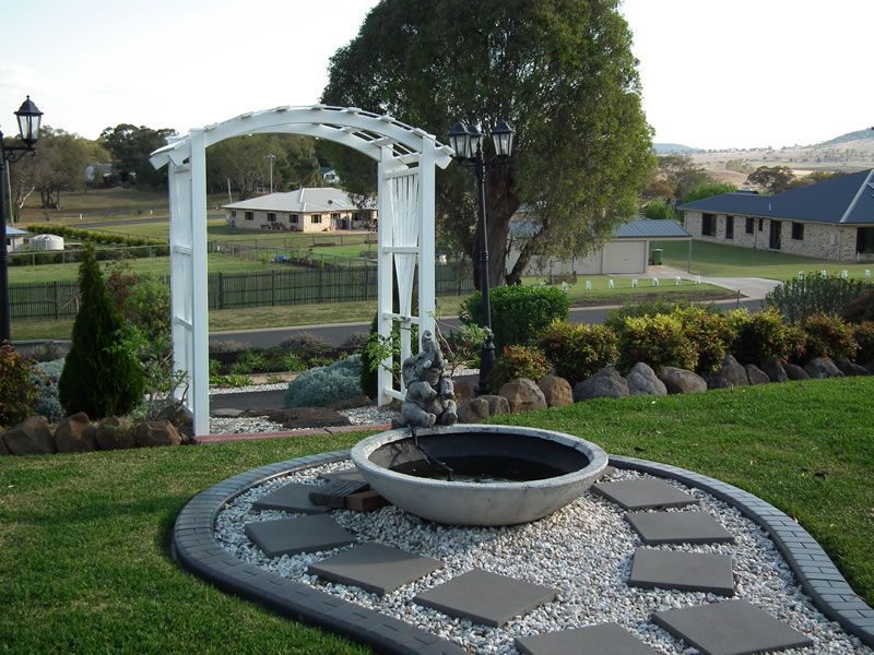 A garden with a white arch and a fire pit