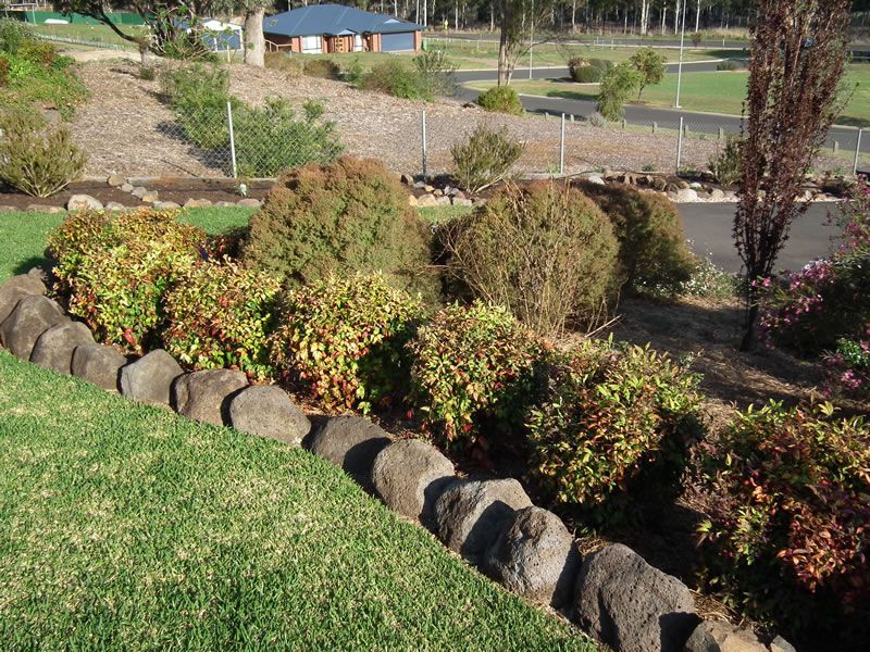 A row of rocks along the edge of a lush green field