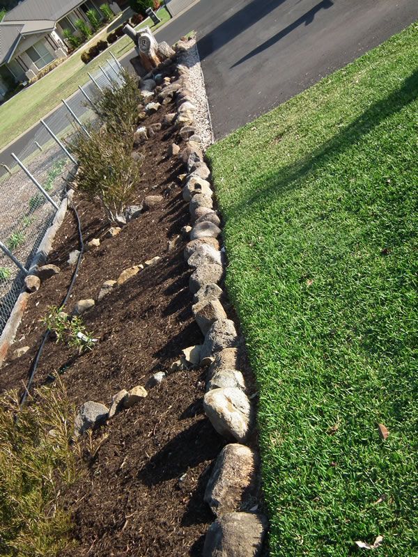 A row of rocks along the edge of a lush green lawn