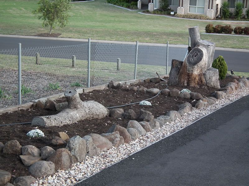 A rock garden with a chain link fence in the background