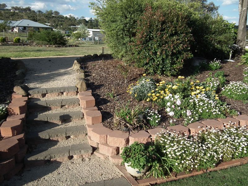 A garden with flowers and stairs and a house in the background