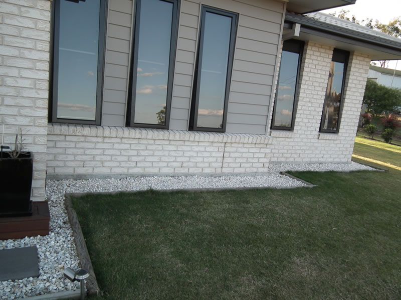 A white brick house with a lawn in front of it